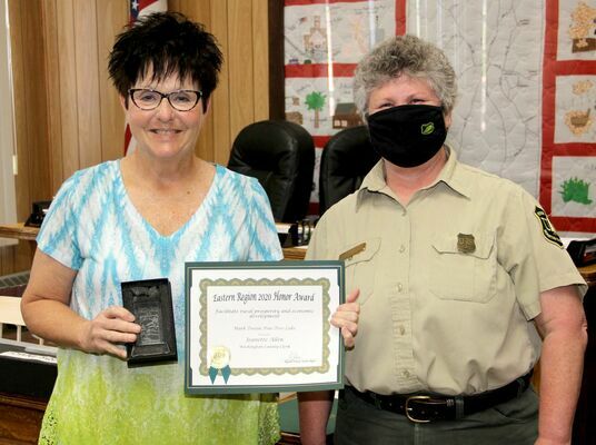 EASTERN REGION HONORS FROM FOREST SERVICE – Becky Ewing, District Ranger for Mark Twain National Forest, Potosi/Fredericktown presented Washington County Clerk Jenny Allen a certificate and a laser engraved glass award on Monday, May 3rd, 2021 at the Washington County Commission meeting at the Courthouse. Ranger Ewing said Mrs. Allen was instrumental in the development and successful installation of a wildfire suppression system at the Pine Tree Lake subdivision on Highway 8 West of Potosi. Mrs. Allen was credited with taking care of project data and financial records for the installation of the dry hydrants.